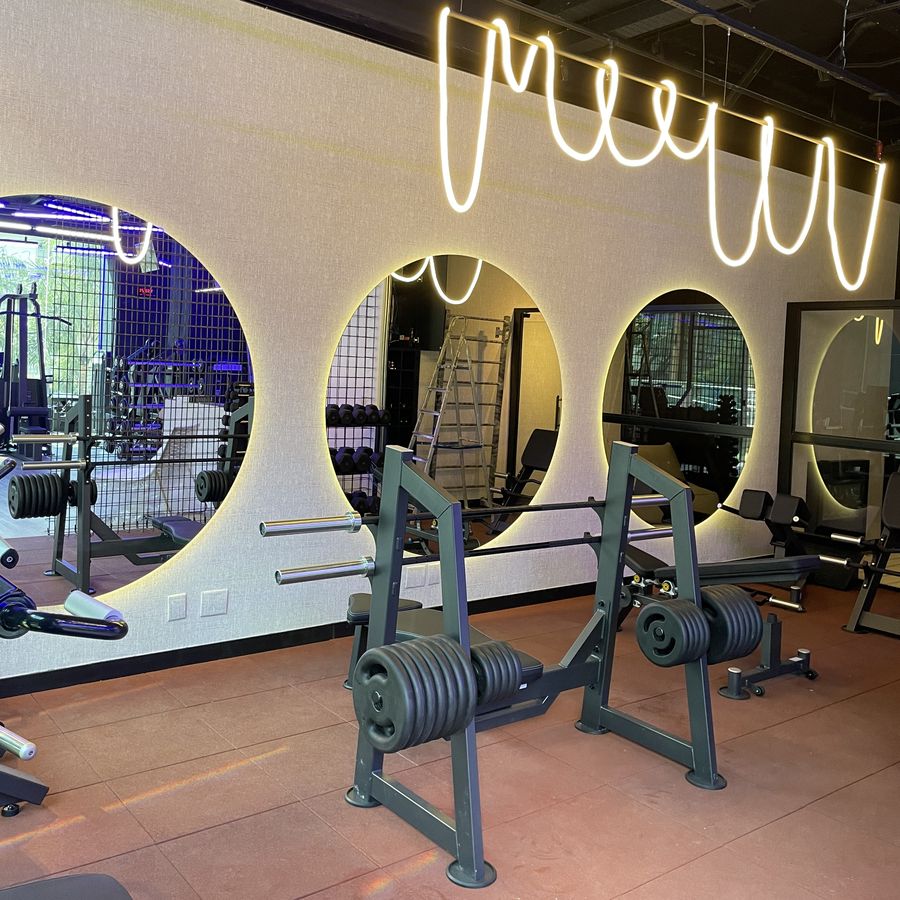 Sala dos espelhos redondos, com piso terracota e aparelhos de musculação